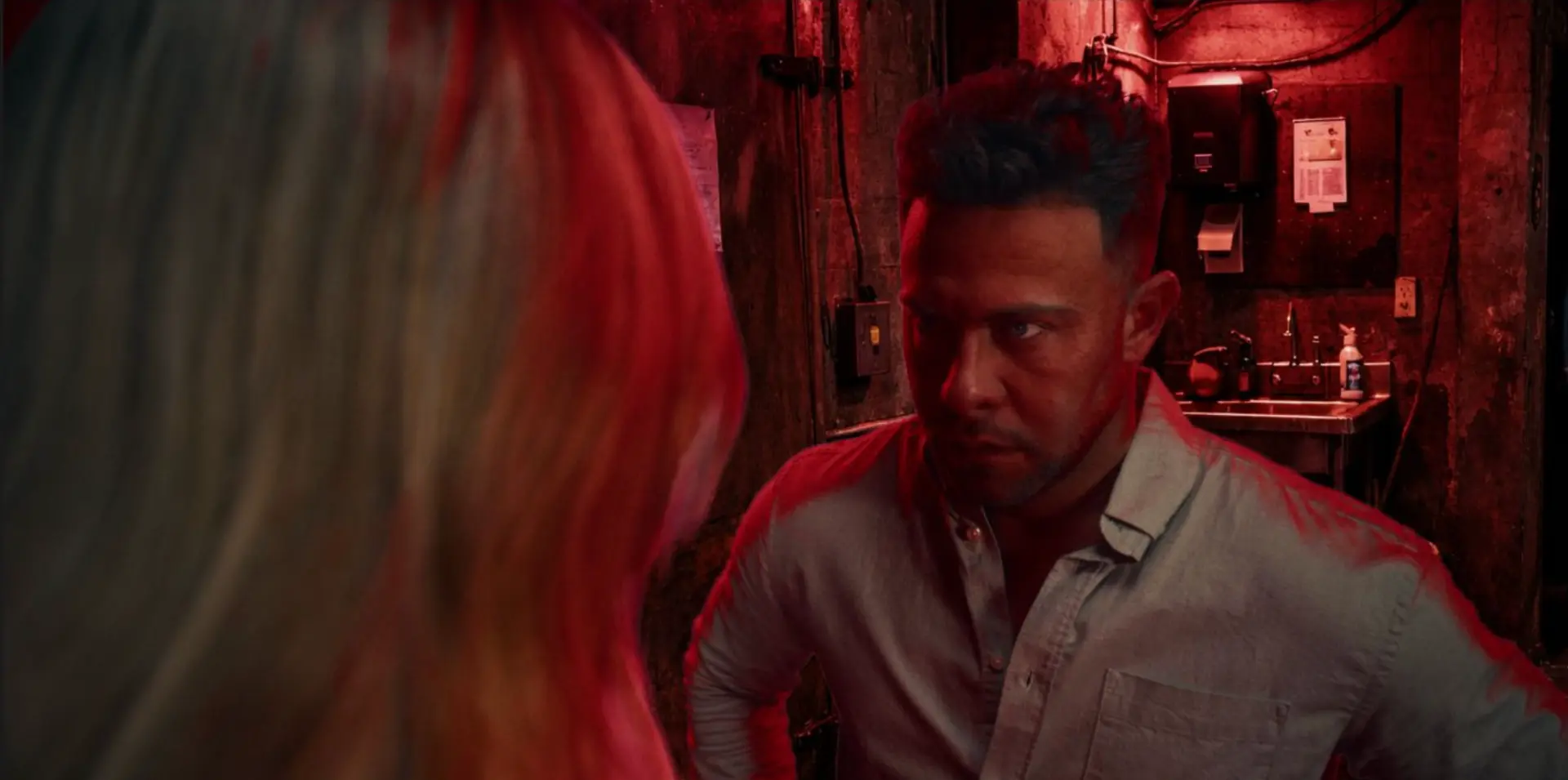 In-game scene: a tense confrontation in a red-lit back room